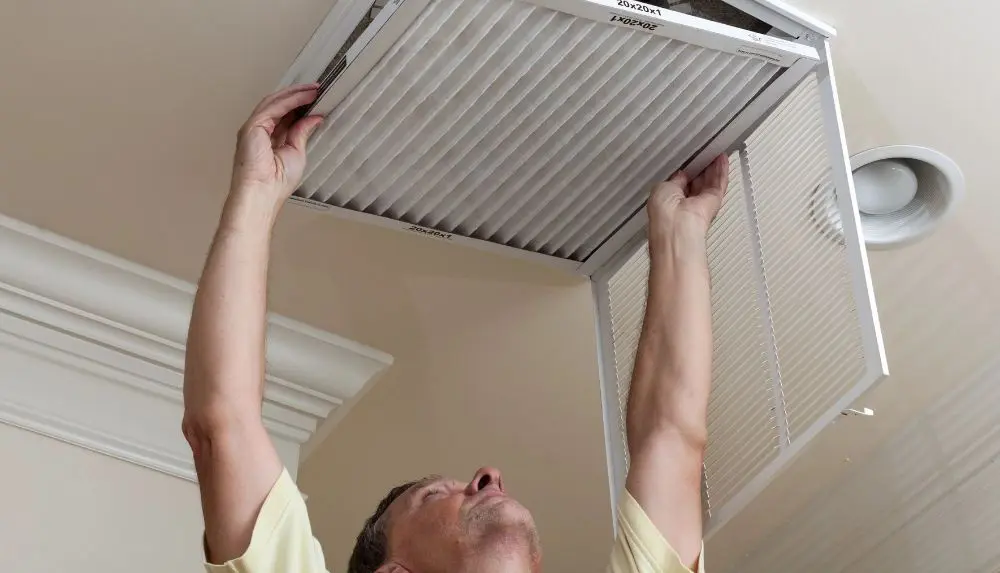 A man holding a filter and fitting it in the ceiling